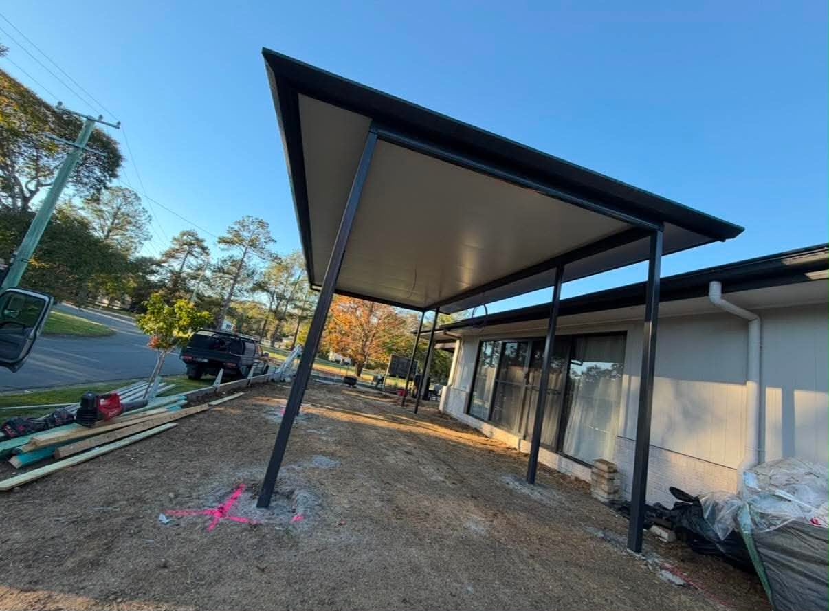 Flat-roof insulated patio with steel posts covering an outdoor area at the rear of a single-storey home