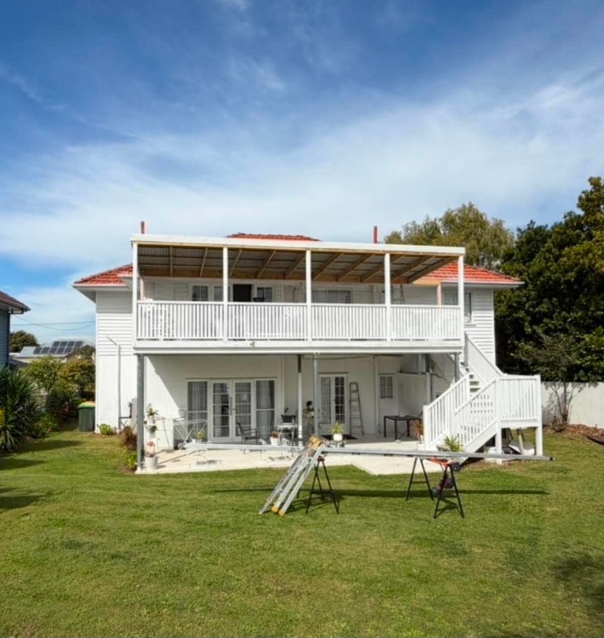 Two-storey home with a new upper-level deck, timber-framed roof structure and white balustrade and stairs